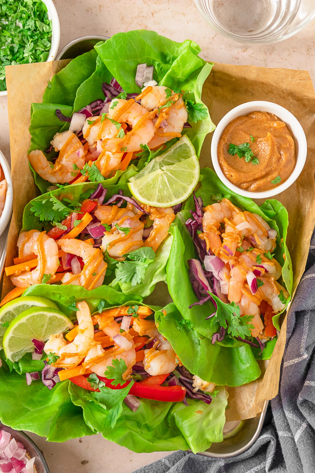 Shrimp Lettuce Wraps with Peanut Sauce on a sheet pan with peanut sauce and limes. 