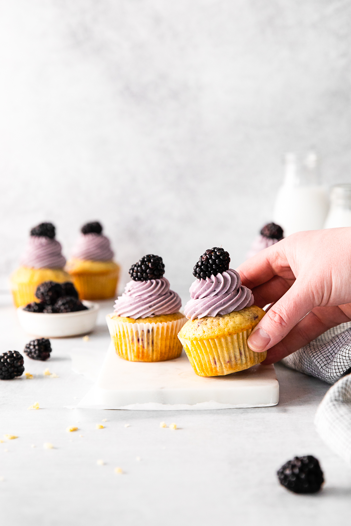 A hand picking up a Blackberry Cupcakes. 