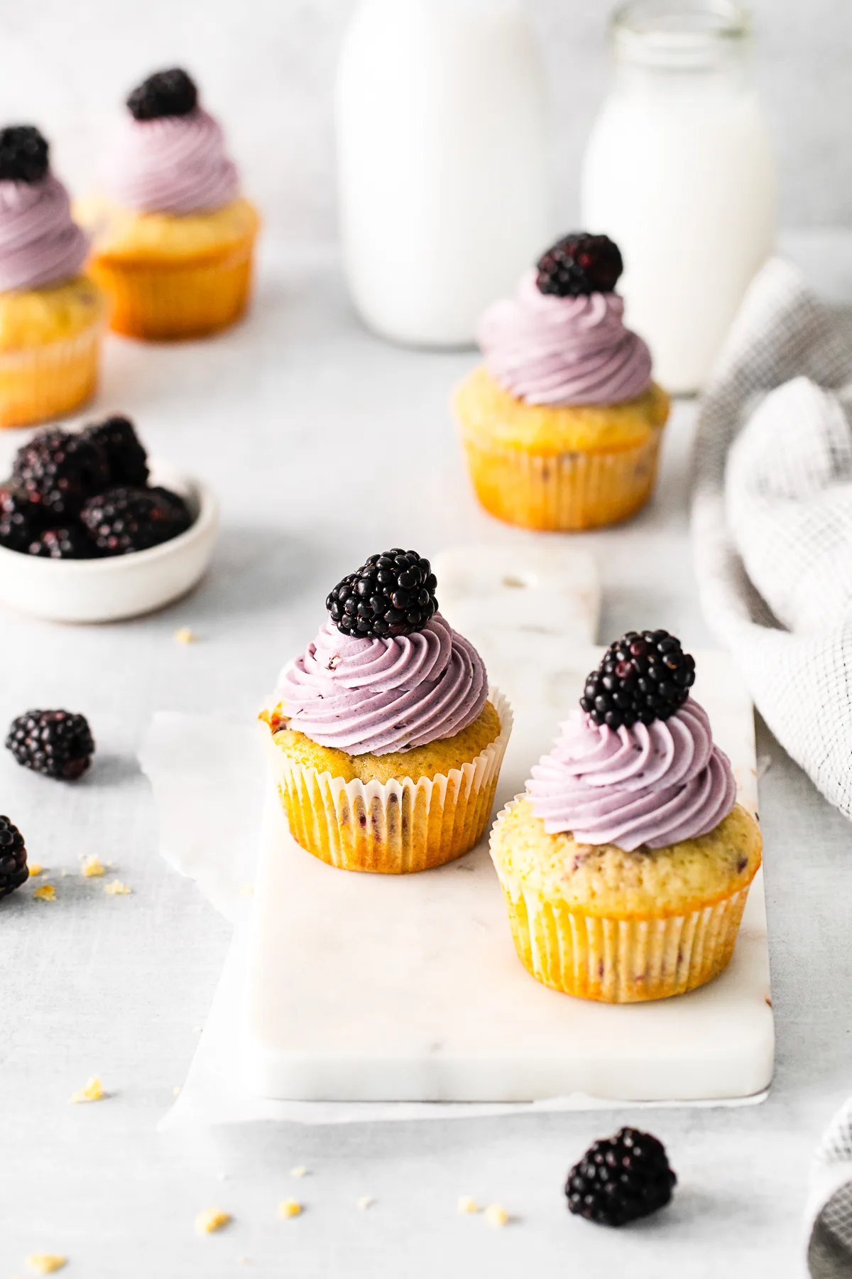Blackberry Cupcakes topped with frosting and a fresh berry. 