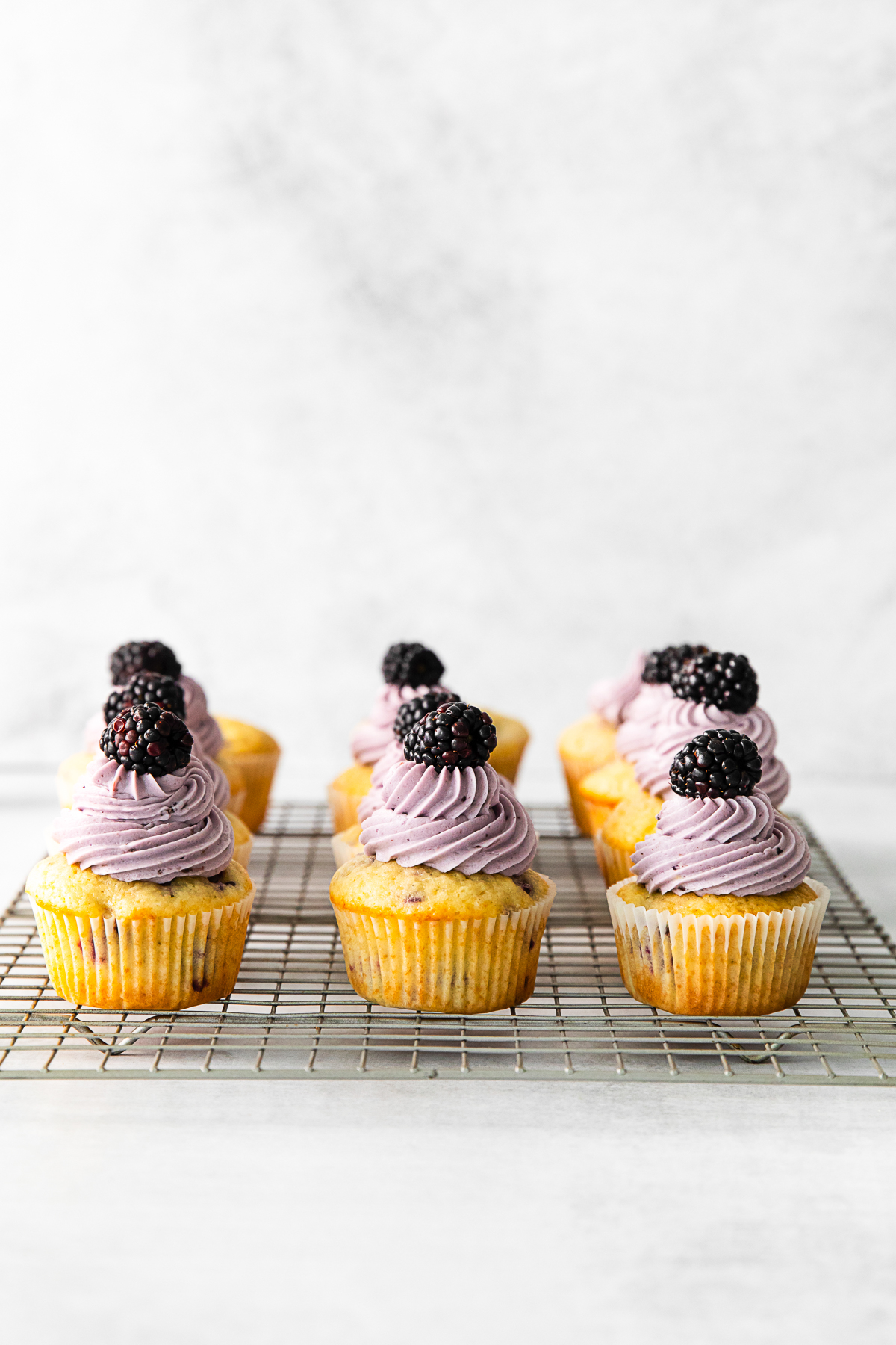 Blackberry Cupcakes on a cooling rack. 