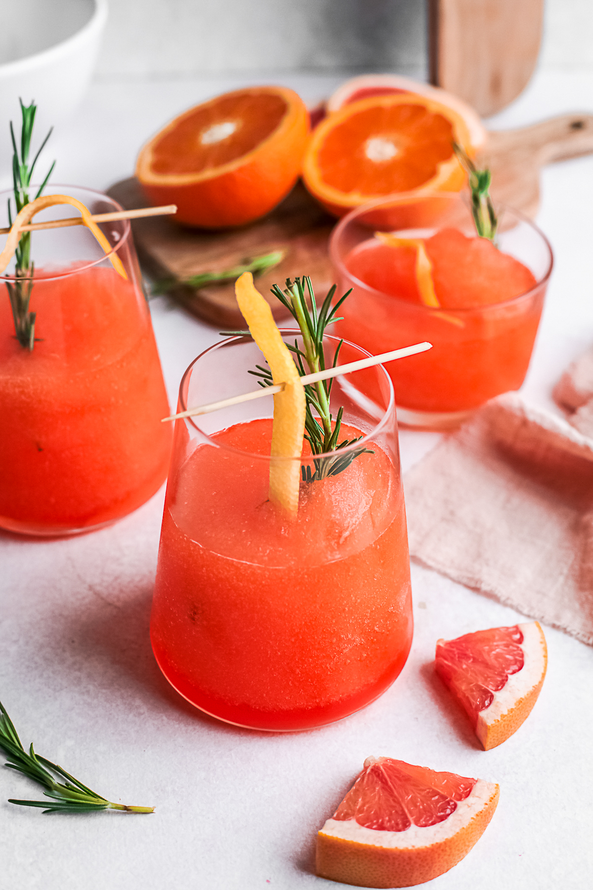 Frozen Aperol Spritz in a cocktail glass garnished with orange and rosemary. 