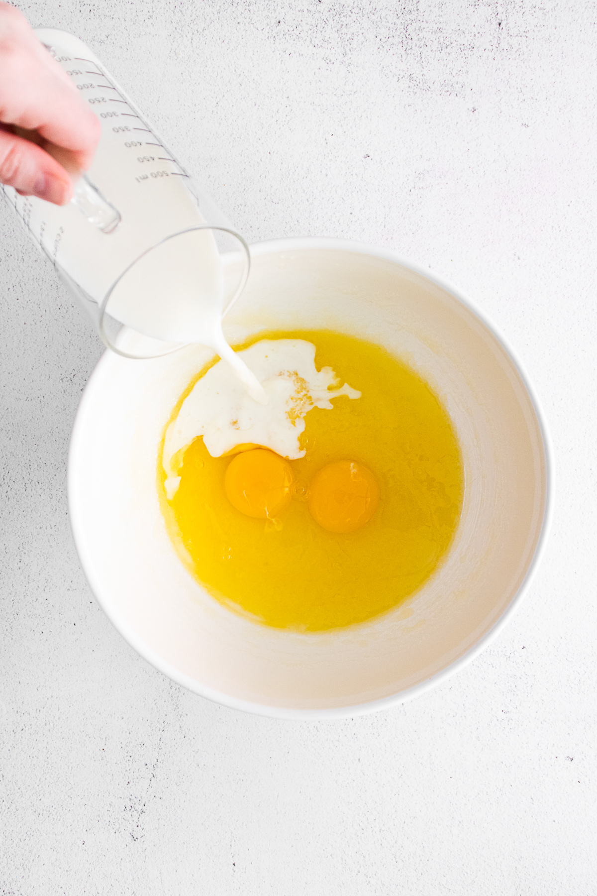 Milk being poured into eggs. 