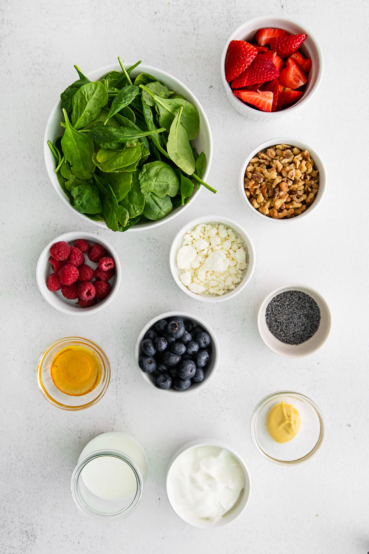 Ingredients to make Spinach Berry Salad on a table. 