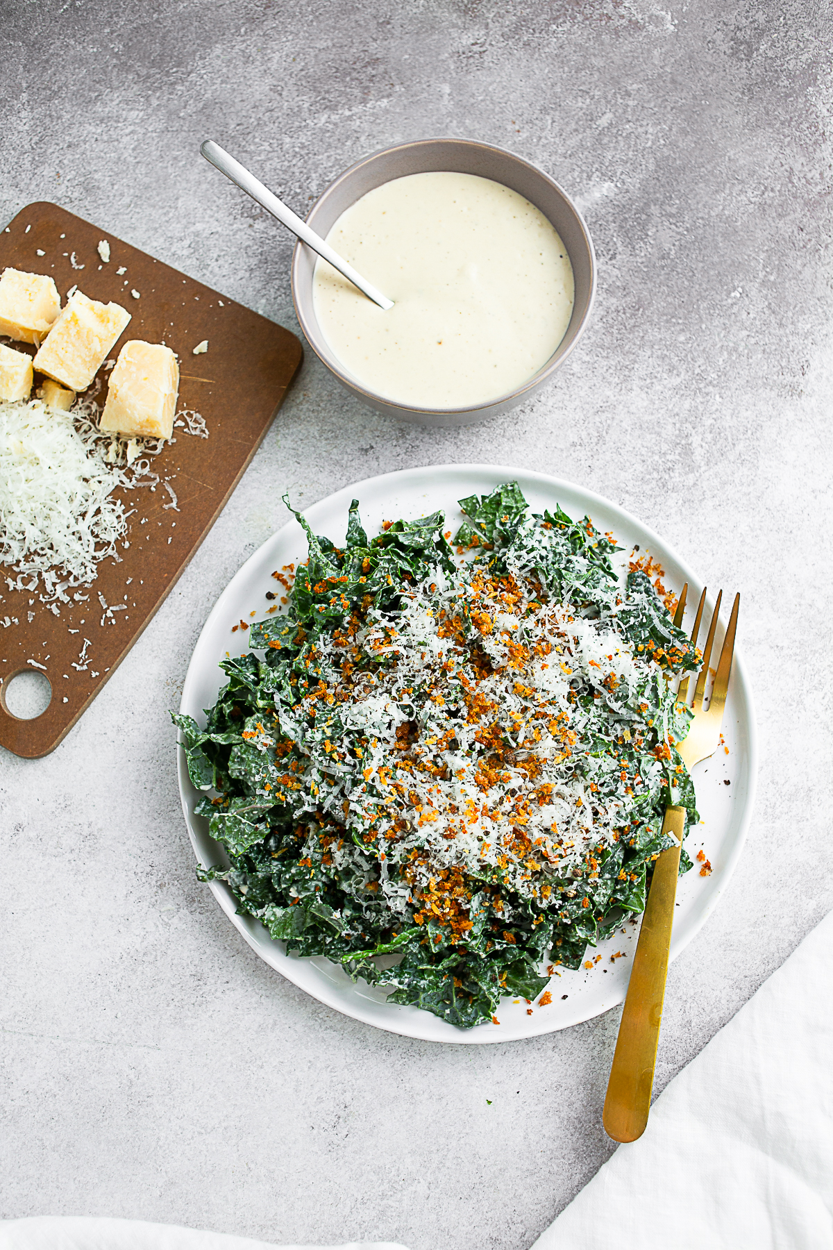 Chopped Kale Caesar Salad on a white plate with a gold fork. 