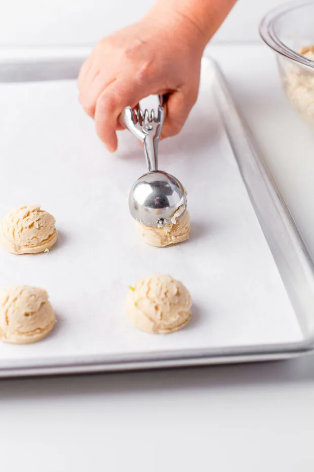 Scooping cookies onto a cookie sheet. 