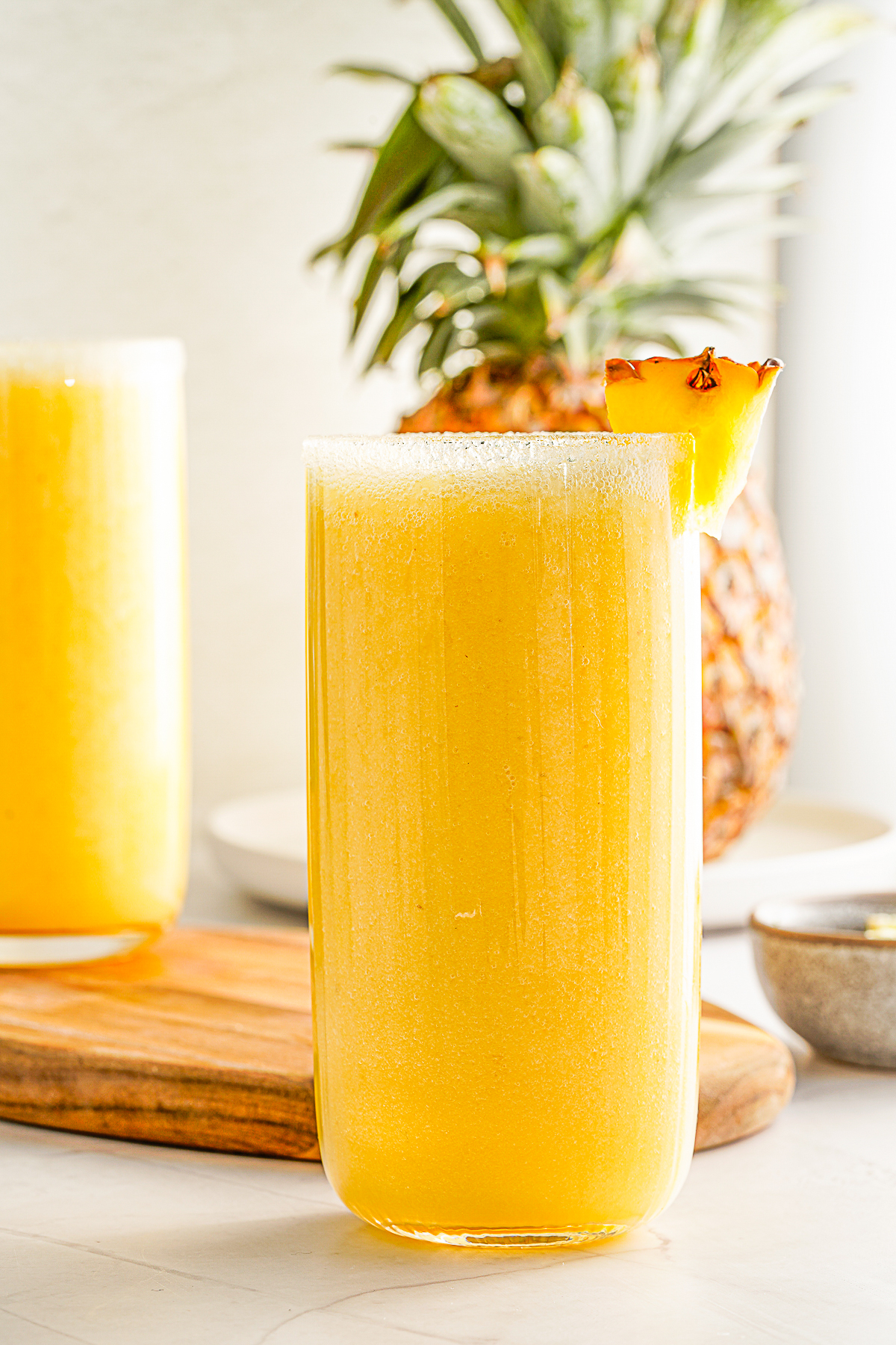 Mango Pineapple Smoothie in a glass with fresh lime and pineapple as garnish. 