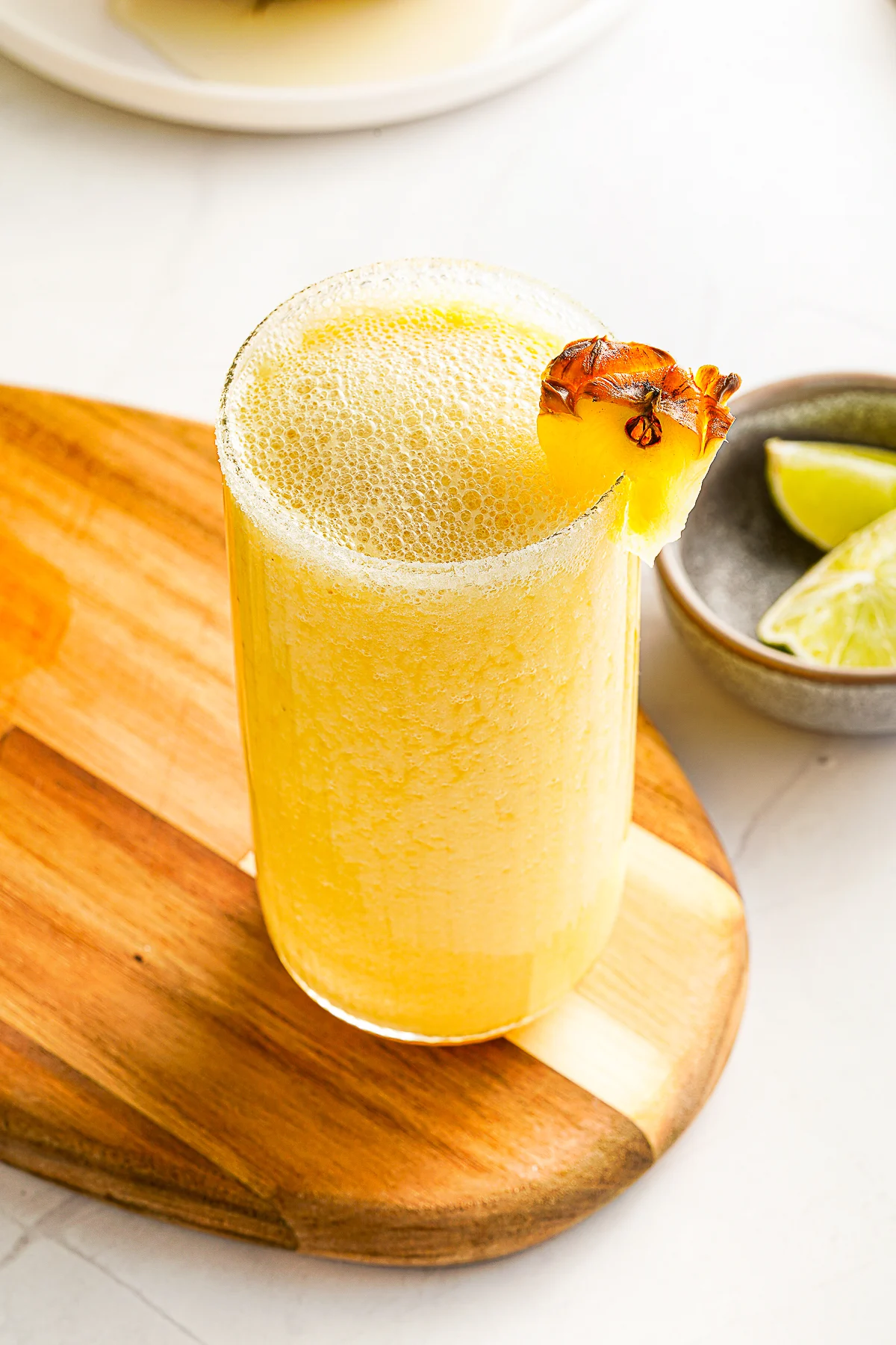 Mango Pineapple Smoothie in a glass with a pineapple on the rim. 