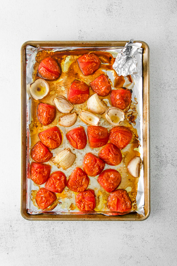 Roasted tomatoes and onions on a sheet pan. 