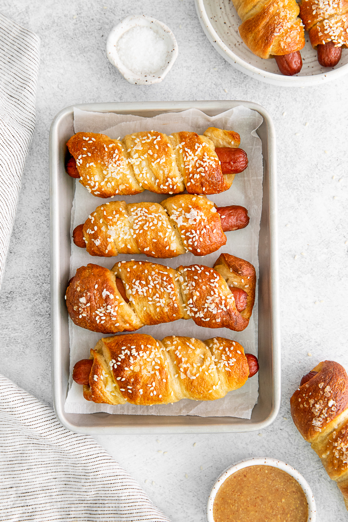 Soft Pretzel Dogs on a sheet pan with dipping sauce.