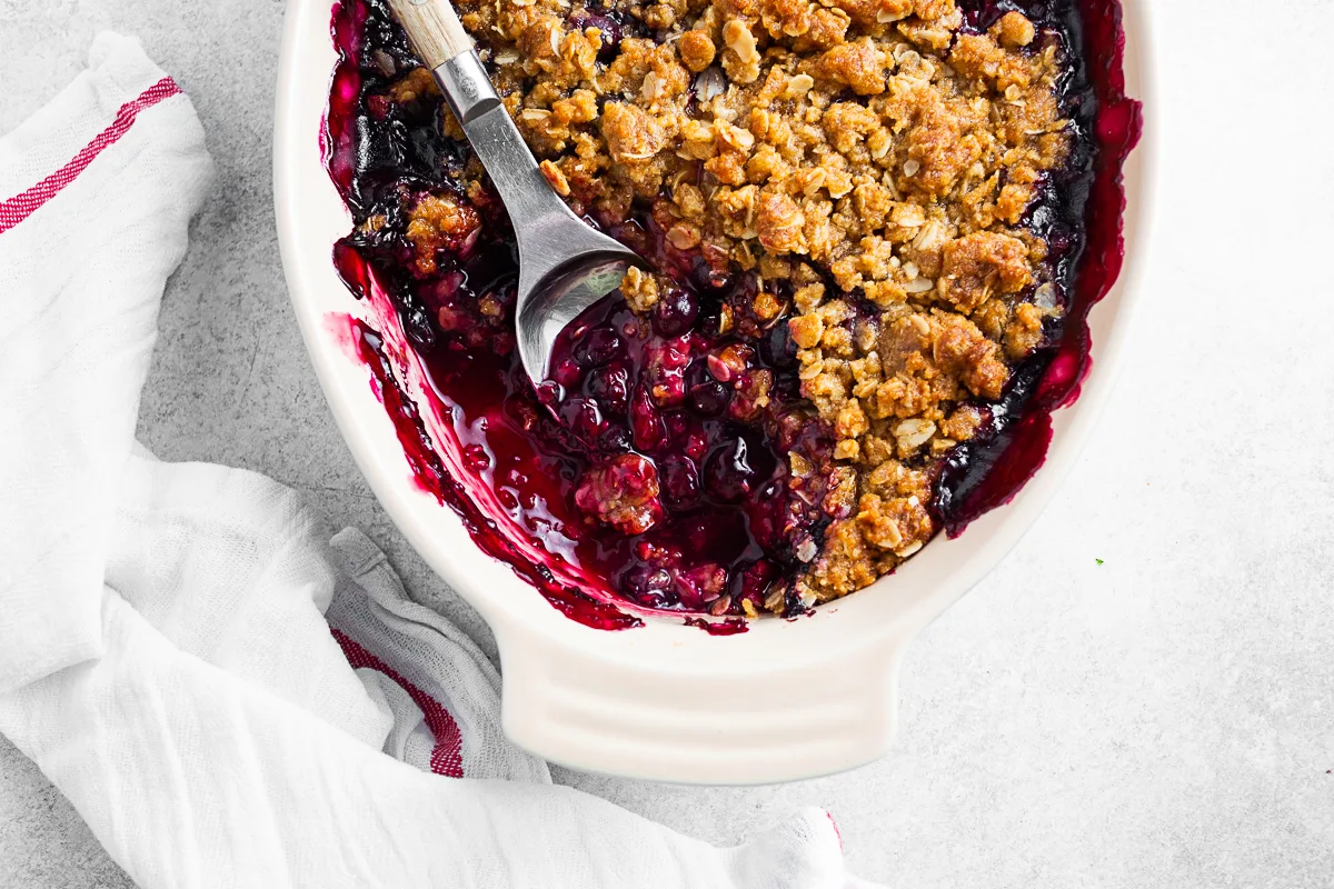 Triple Berry Crisp in a pan with a spoon. 