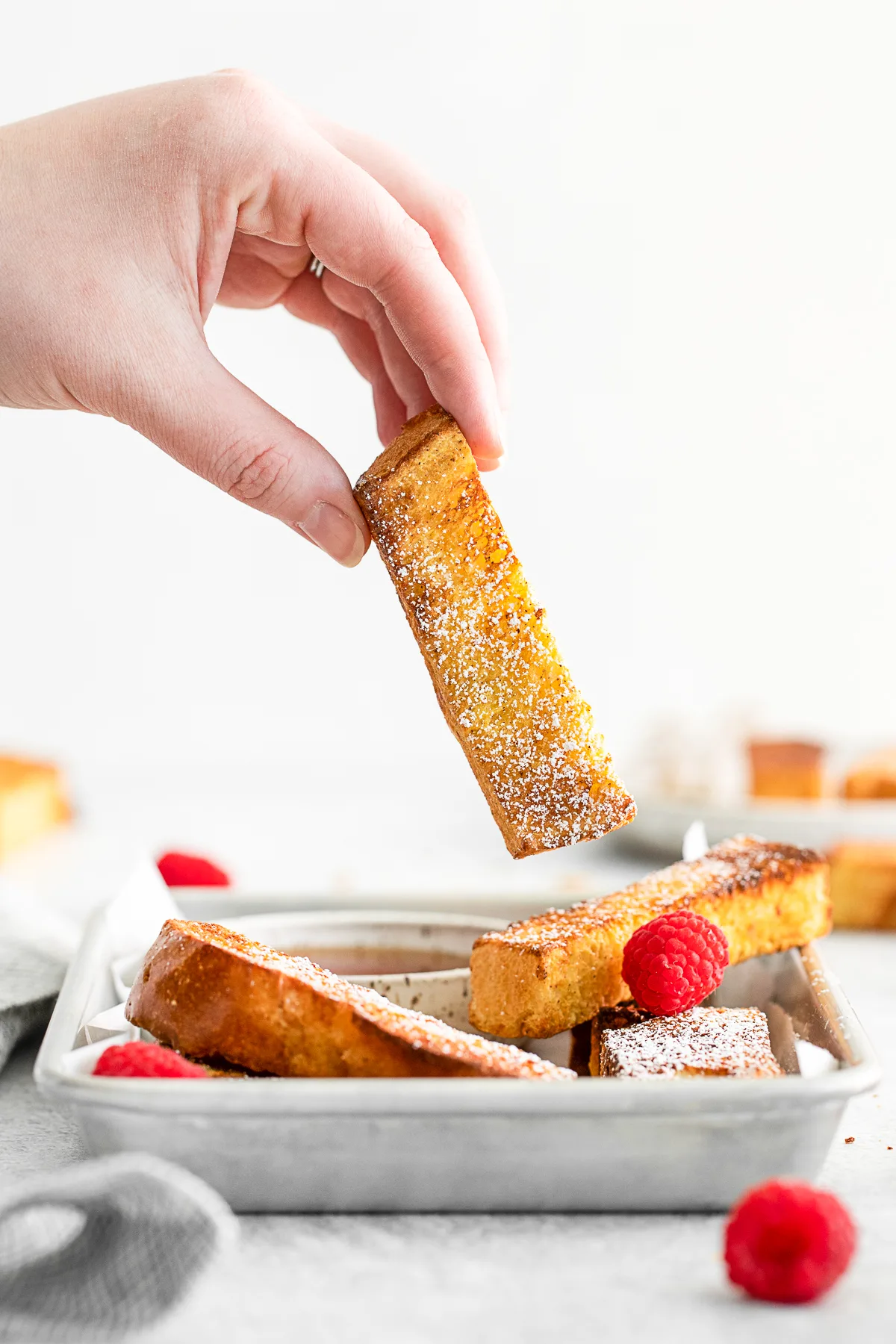 A hand picking up a french toast stick. 