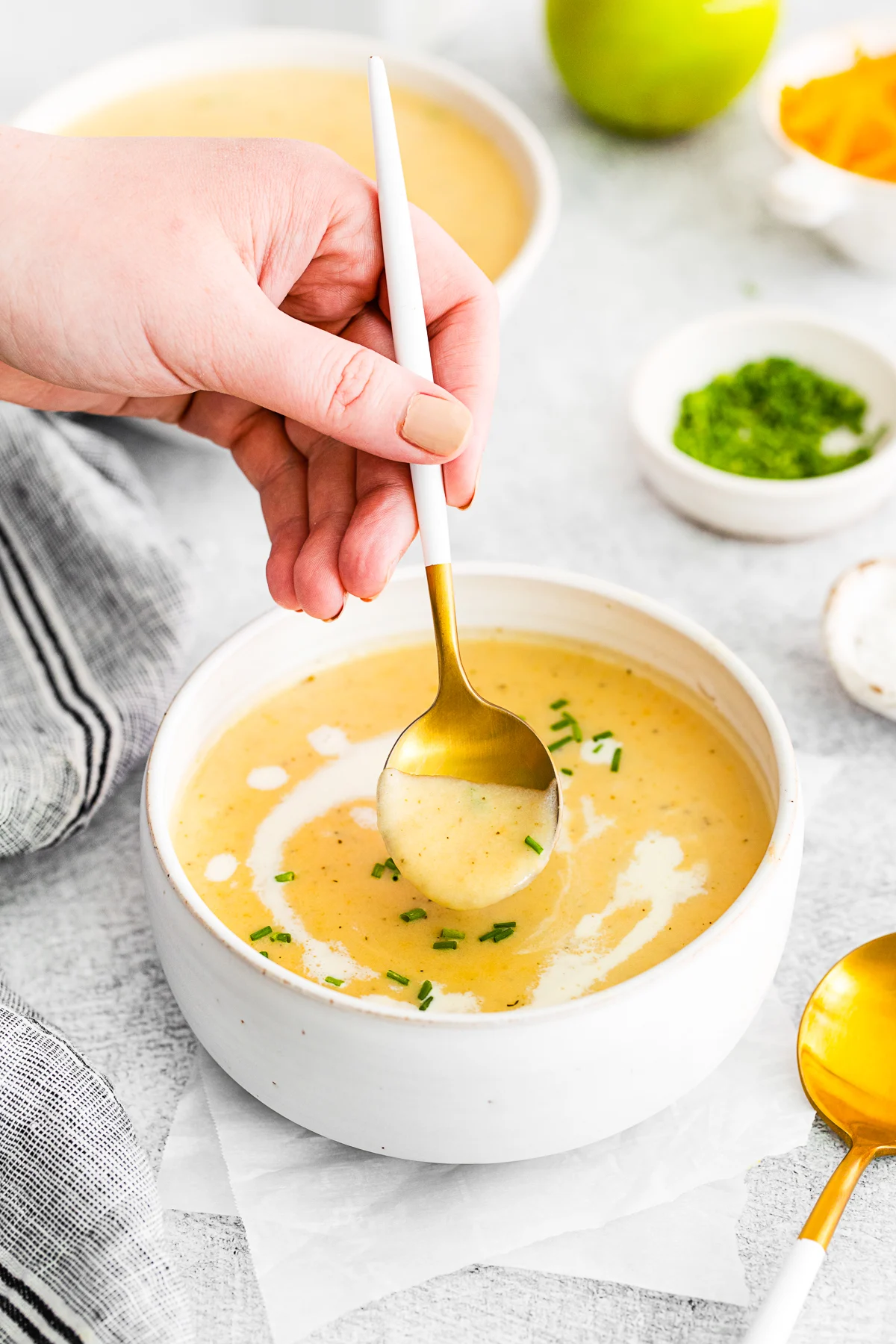A hand spooning out a bite of Apple Cheddar Soup. 