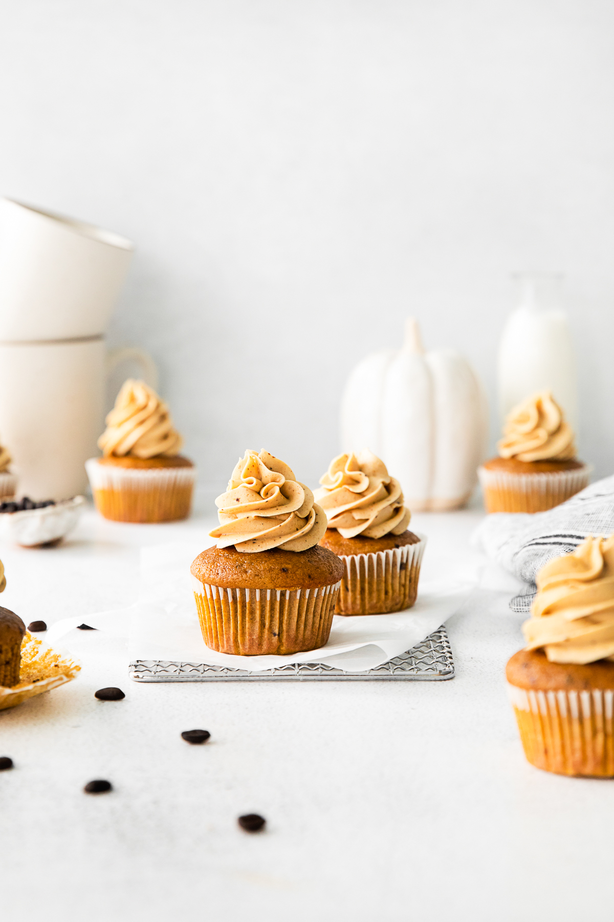 Pumpkin Spice Latte Cupcakes sitting on a table with cupcakes around it. 