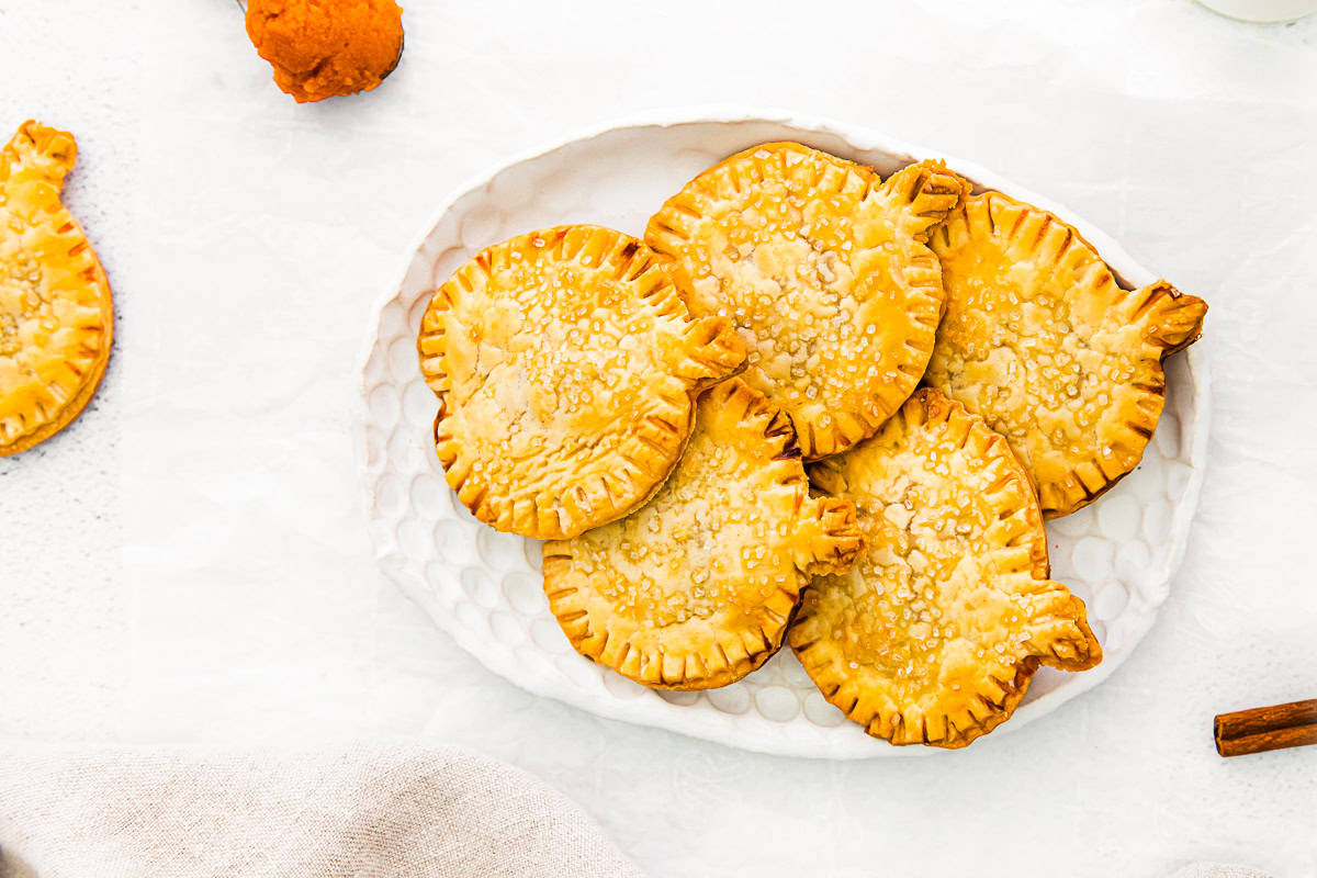 Pumpkin Hand Pies sitting on a white serving platter. 