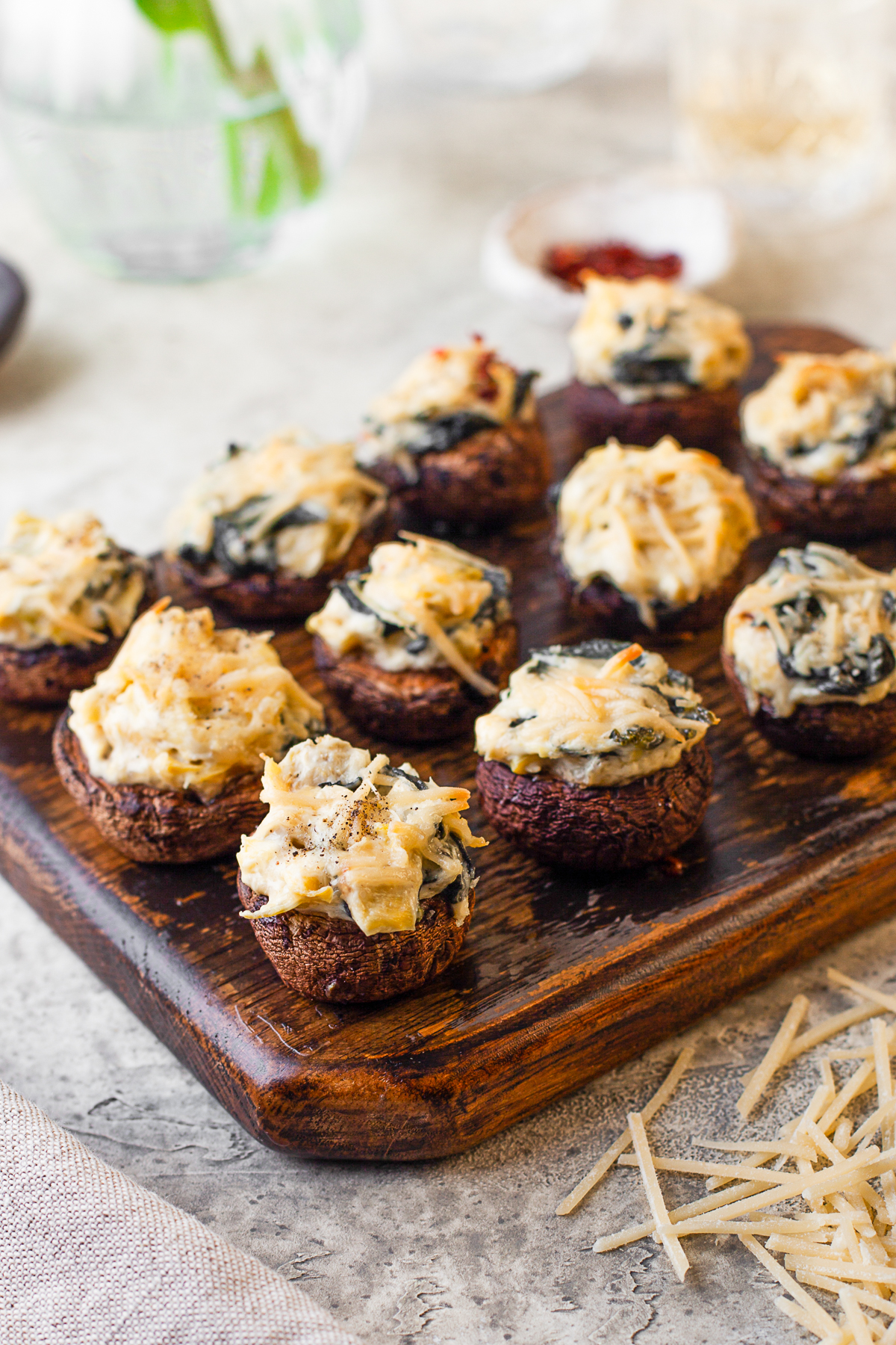 Spinach Artichoke Stuffed Mushrooms on a wooden serving tray. 