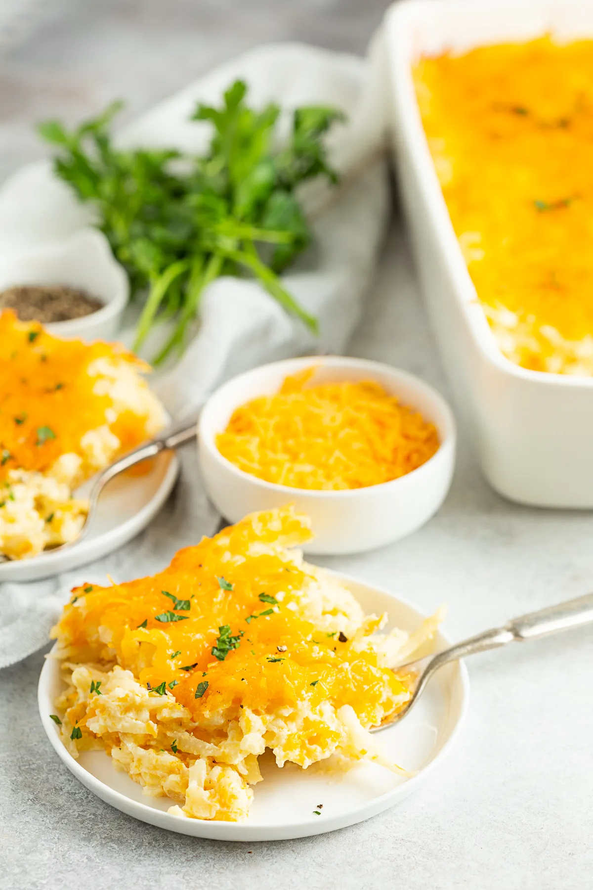 Cheesy Potatoes (Funeral Potatoes) on a plate with a fork. 