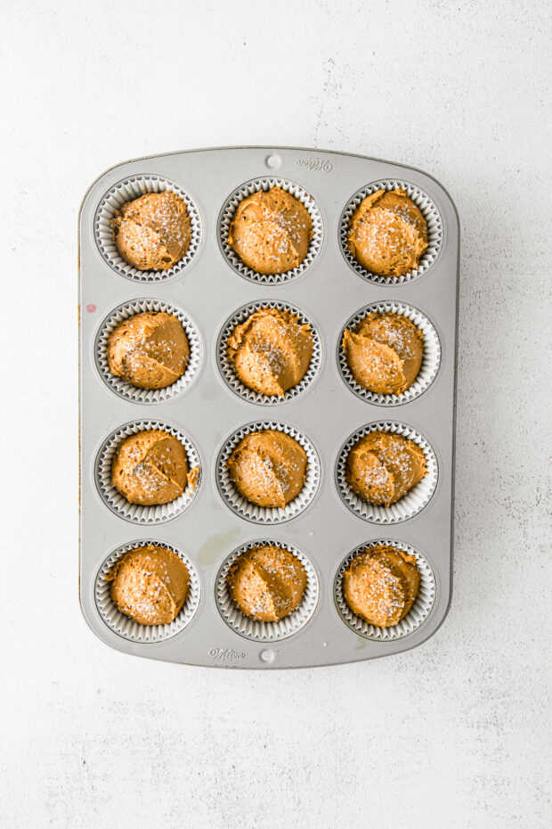 Uncooked muffins in a baking tin. 