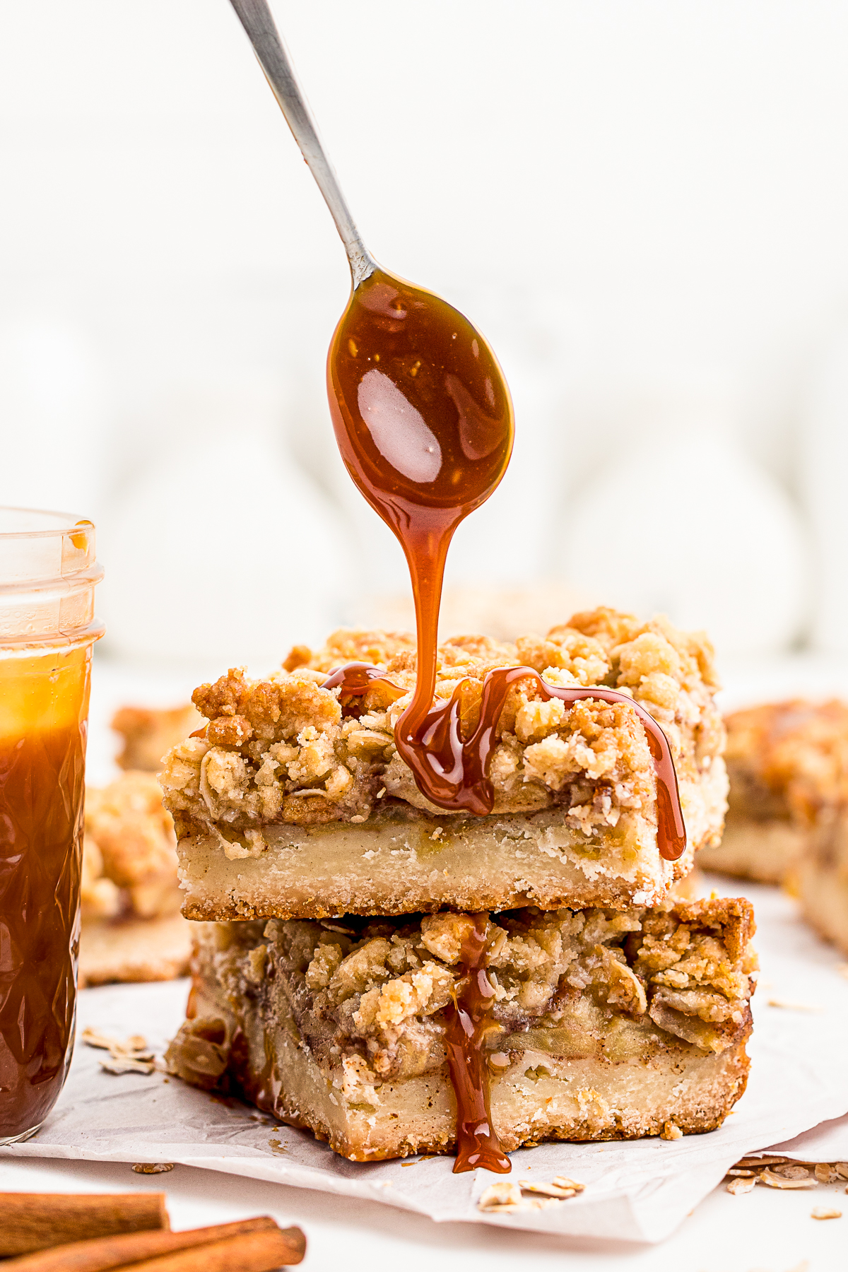 Salted Caramel Sauce being drizzled off a spoon on top of an apple pie bar. 