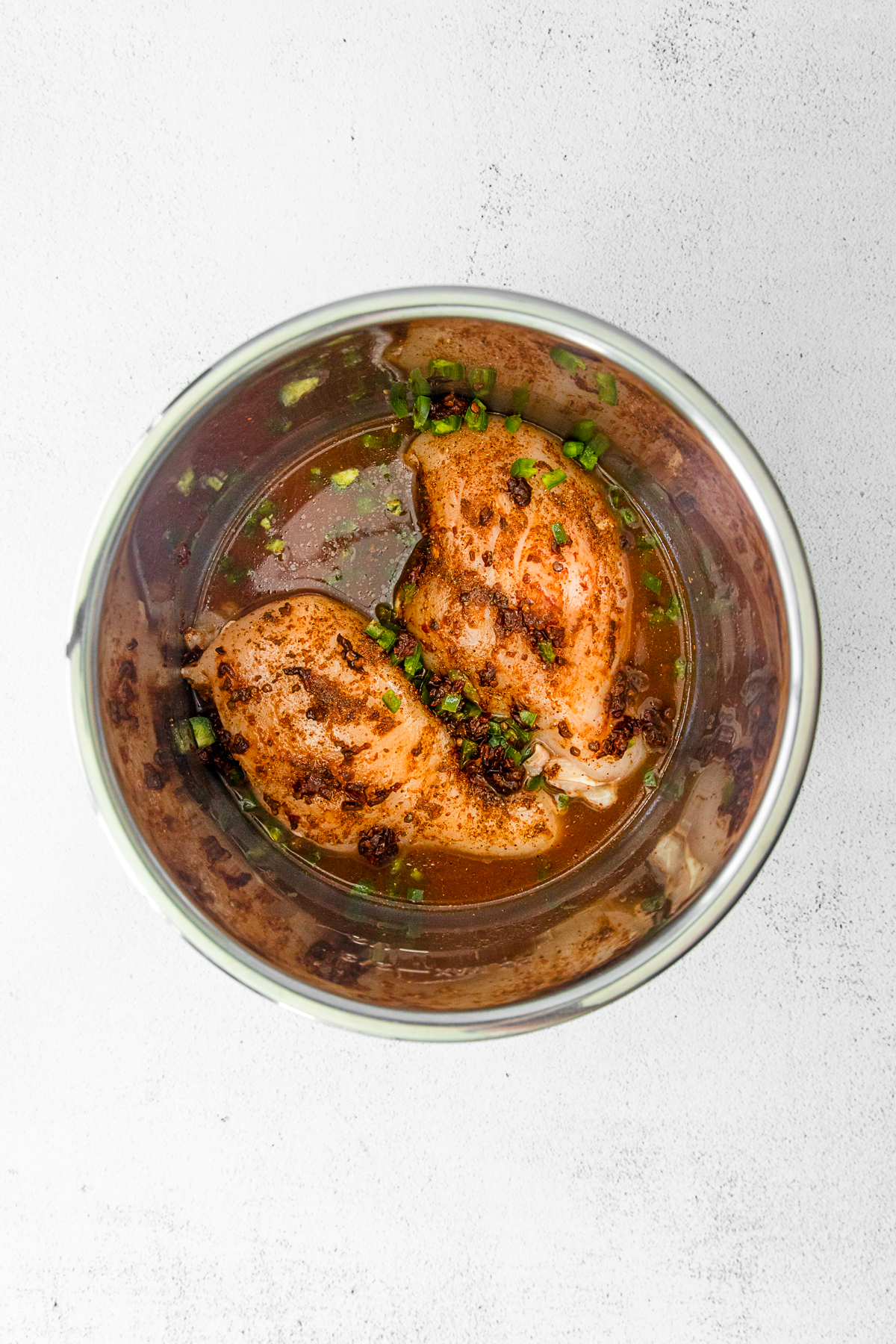 Raw uncooked chicken with spices in an Instant Pot pot. 
