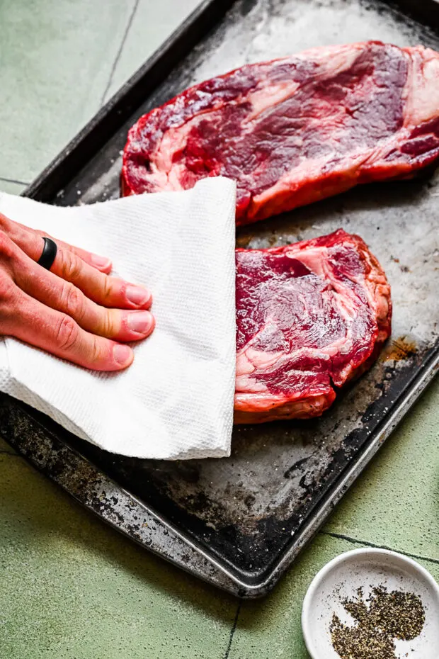 Blotting steaks with a paper towel. 