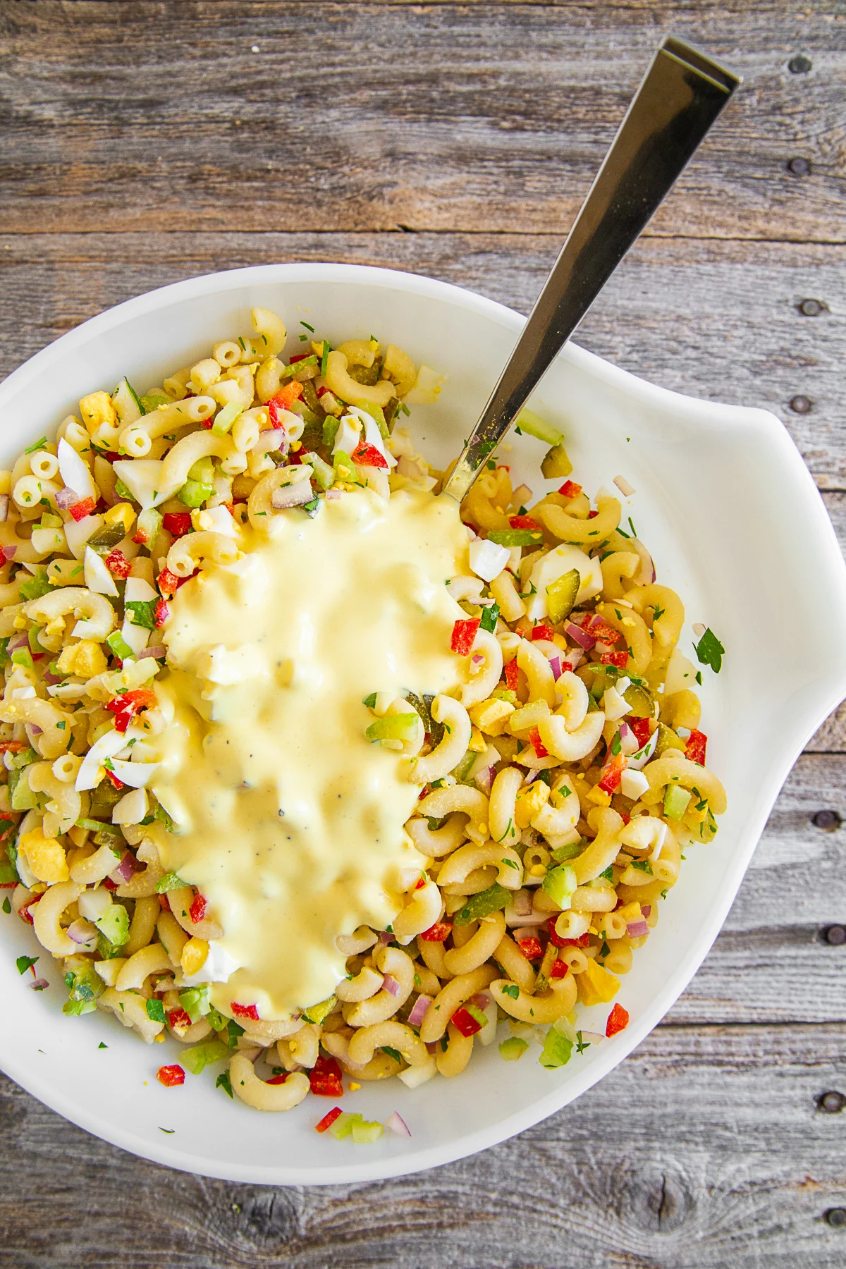 Classic Macaroni Salad in a bowl with dressing poured on top. 