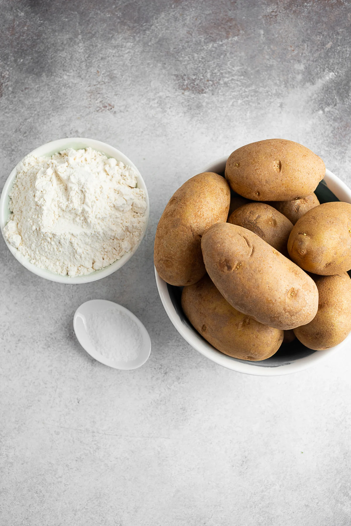 Potatoes, flour, and kosher salt on a table. 