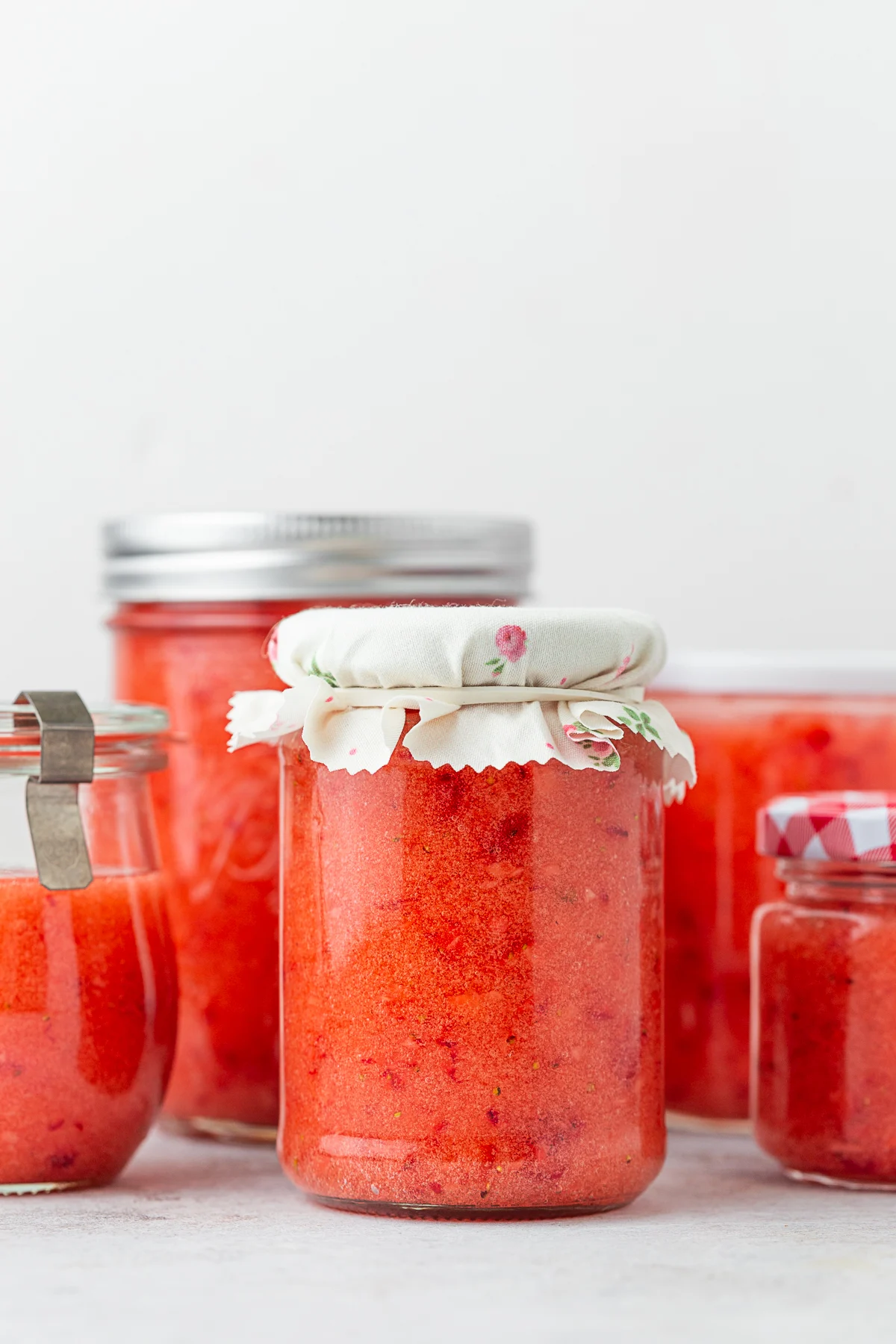 Glass jars filled with strawberry freezer jam. 